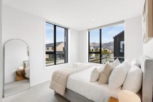 ein weißes Schlafzimmer mit einem großen Bett und großen Fenstern in der Unterkunft Modern 3-Bed Villa with Mountain Views in Wanaka
