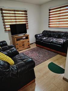 a living room with a black leather couch and a flat screen tv at Kabañas Bosque De Alamos in Puerto Aisén