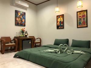 een slaapkamer met een groen bed in een kamer bij สมายด์ ฮ่อมนา เรสเฮาท์ Smile Homna Resthouse in Ban Mae Chong +67 foto's