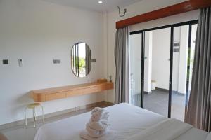 a bedroom with a white bed and a mirror at Habitat Boutique Dive Resort in Tulamben