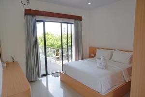 a bedroom with a white bed and a balcony at Habitat Boutique Dive Resort in Tulamben