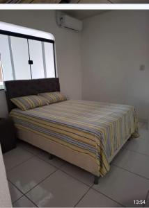 ein Bett in einem weißen Zimmer mit einem Fenster in der Unterkunft Casa linda in Ananindeua