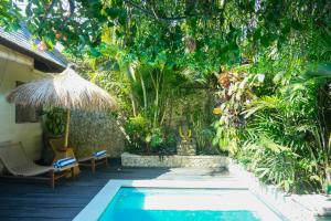 a swimming pool in a garden with a umbrella at Aloha Beach House Bingin Villas in Uluwatu