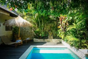 a swimming pool in a garden with a umbrella at Aloha Beach House Bingin Villas in Uluwatu