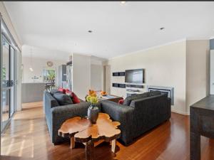 a living room with two couches and a table at Cozy Water-View 2-Bdrm Suite in North Shore in Auckland