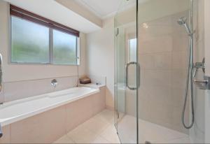 a bathroom with a shower and a tub and a sink at Cozy Water-View 2-Bdrm Suite in North Shore in Auckland +3 photos