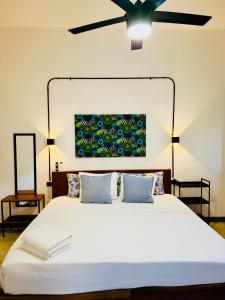 Un dormitorio con una cama grande blanca con ventilador de techo. en Casa Lluavi - Caliope, en Mérida