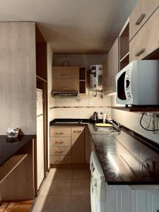 eine kleine Küche mit weißen Schränken und einer Mikrowelle in der Unterkunft Departamento Premiun Victoria I in San Juan