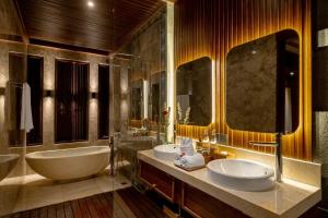 a bathroom with two sinks and a tub and a large mirror at Nauma Ubud Villa in Ubud