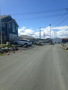 an empty street with a blue house and a truck at Jubilee Ocean Front in Topsail