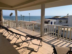 a porch with chairs and the ocean in the background at Sunsets & Surf Beach House near Puerto Nuevo in Raulis