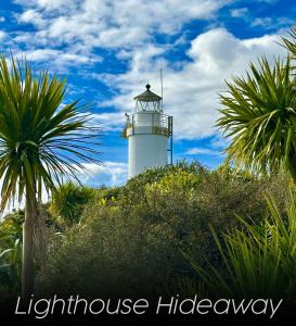 a lighthouse on top of a hill with palm trees at Lighthouse-hideaway in Cape Foulwind