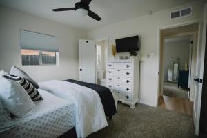 a bedroom with a bed and a dresser and a television at The White House, A Unique ABQ Stay in Central Location near Uptown in Albuquerque