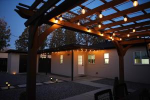 a patio with a wooden pergola with lights on it at The White House, A Unique ABQ Stay in Central Location near Uptown in Albuquerque
