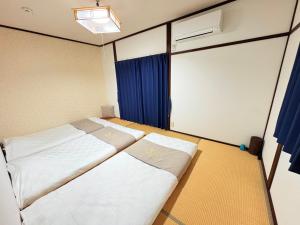 two beds in a room with blue curtains at 夏様四条大宮 四条大宮駅5分 京都市中心部 一棟一組貸切 広い庭付き一戸建て in Kyoto