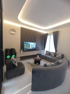 ein Wohnzimmer mit zwei Sofas und einem Fernseher in der Unterkunft QueeNdra Villa in Tlekung