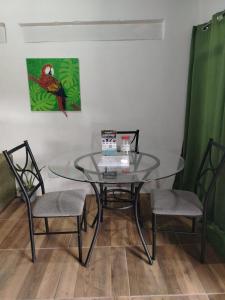 a glass table with two chairs and a painting on the wall at Apartamentos GoZu # 1 in Puerto Viejo