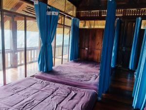 a bed in a room with blue drapes at Háng Đồng Ecolodge in Bắc Yên