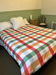 a bed with a colorful plaid blanket on it at Grandad's farmhouse in Northcliffe +5 photos