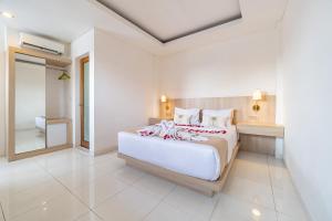 a bedroom with a large white bed and a mirror at Srikrisna in Seminyak