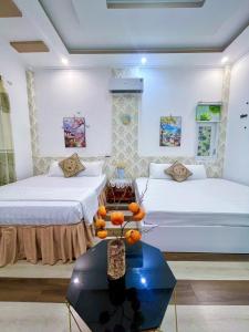 a room with two beds and a table with oranges on it at Hoàng Nga Apartment Phan Thiết in Phan Thiet
