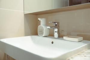 een witte wasbak met een föhn en een spiegel bij The Luxe Haven at BGC in Sampong