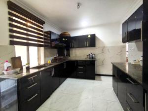 een keuken met zwarte kasten en marmeren vloeren bij White lotus villa in Ragama