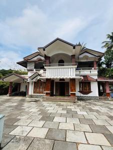 a house with a stone driveway in front of it at whisperingstrem's RIVER view homestay in Padinjarathara