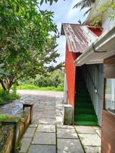 a brick walkway next to a red building at whisperingstrem's RIVER view homestay in Padinjarathara