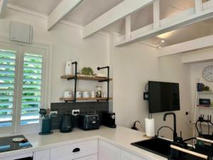 a kitchen with white cabinets and a flat screen tv at The Stables in Armidale