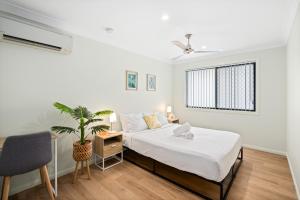 a white bedroom with a bed and a plant at Smart Suites Self Check-in Apartments - Sunnybank Station in Brisbane