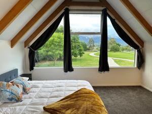 a bedroom with a bed and a large window at Kaikōura Mountain View Lodge in Kaikoura