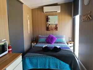 a bedroom with a bed with purple and purple pillows at Kalmya Farm Retreat by Tiny Away in Nanango
