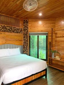 a bedroom with a bed and a large window at Kovie Hoa Lac Xanh Resort in Nam Giao