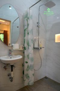 a bathroom with a sink and a shower with a mirror at Pondok Wanagiri in Gitgit