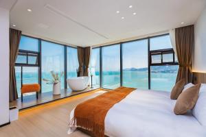 een slaapkamer met een groot bed en grote ramen bij Qingdao Momer Cliff Ocean View Villas in Qingdao