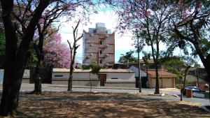 un parque con árboles y un edificio al fondo en Acosta Ñu Apart Hotel, en Asunción