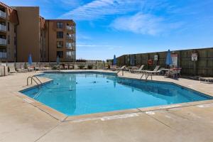 a large swimming pool with chairs and a building at Coast is Clear- Oceanfront Escape at Topsail Dunes in North Topsail Beach