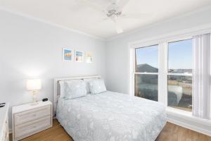 a white bedroom with a bed and a window at Coast is Clear- Oceanfront Escape at Topsail Dunes in North Topsail Beach +48 photos