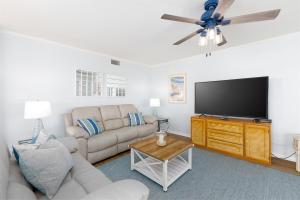 a living room with a couch and a flat screen tv at Coast is Clear- Oceanfront Escape at Topsail Dunes in North Topsail Beach