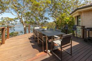 a wooden deck with a table and chairs on it at Luminara Luxury Lakefront in Smiths Lake
