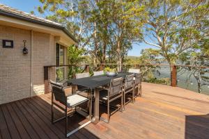 a wooden deck with a black table and chairs at Luminara Luxury Lakefront in Smiths Lake