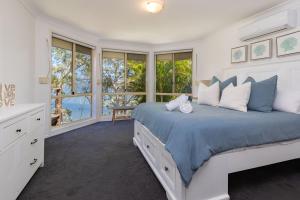 a white bedroom with a large bed and windows at Luminara Luxury Lakefront in Smiths Lake