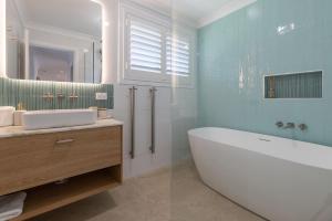 a bathroom with a tub and a sink and a mirror at Luminara Luxury Lakefront in Smiths Lake +18 photos