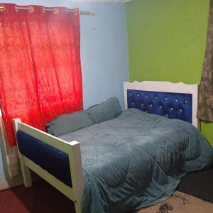 a bedroom with a bed and a red curtain at Sacred Heart Apartments BNB & Hostels Meru Town in Meru