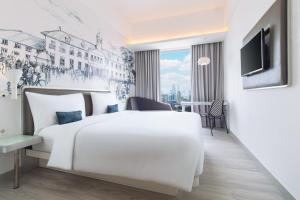 Una habitación de hotel con una cama blanca y un televisor. en YELLO Hotel Harmoni, en Yakarta