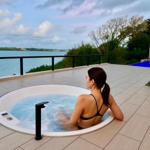 a woman in a bathing suit sitting in a hot tub at the 478 -pool & spa- Miyakojima Luxury Villa in Miyako Island