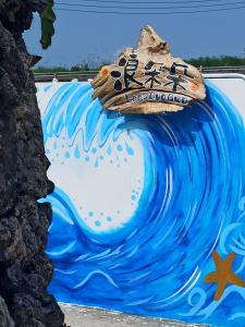 un mural de una ola con una tabla de surf encima en Lang duo duo Homestay, en Huxi