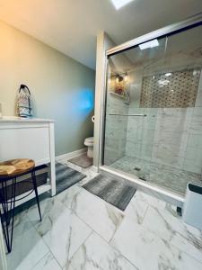 a bathroom with a glass shower with a table and a stool at Paradise Island escape Riverfront in Clay, NY in Clay +59 photos