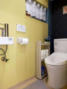 a bathroom with a white toilet and a yellow wall at 時の宿 in Kawagoe
